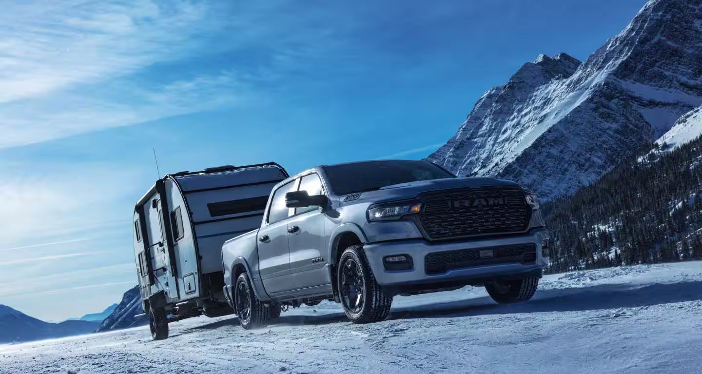 2027 RAM 1500 towing a trailer in a winter landscape