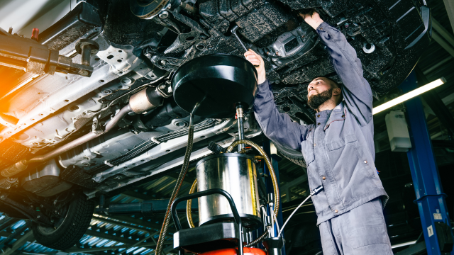 RAM service technician changing oil under a vehicle